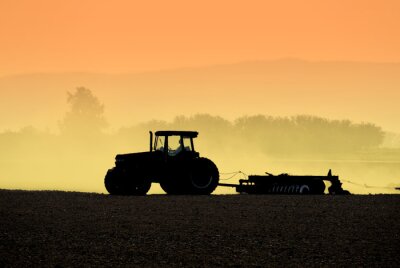 Obraz Traktor na polu podczas zachodu słońca